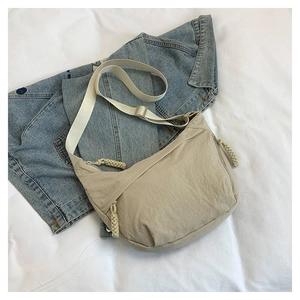 Détail d'un sac bandoulière beige en nylon avec poches zippées et tirettes tressées