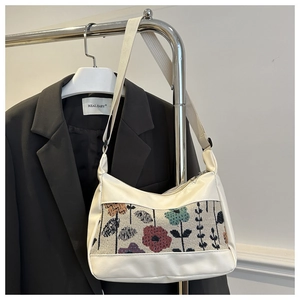 Detail of vintage floral embroidery panel on white PU leather handbag with metal zipper
