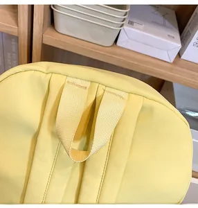 Detailed macro shot of the reinforced top handle and stitching on the bright yellow backpack