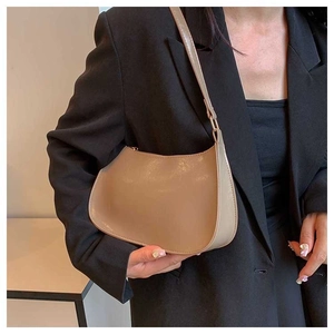 Detailed close-up of khaki faux leather hobo bag worn by a model in a black suit