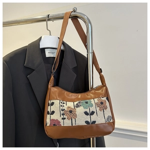 Detail of floral tapestry fabric and brown PU leather trim on fashionable shoulder bag