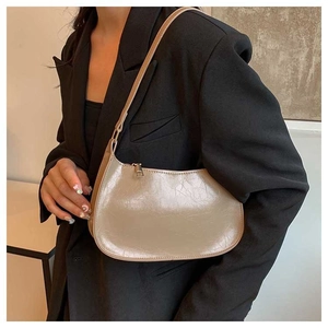Close-up of champagne vintage pleated leather baguette bag worn with a black blazer