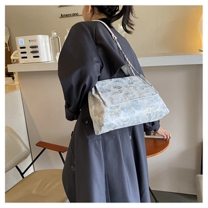 Détail du sac jacquard bleu clair à motif papillon avec chaîne argentée et cuir
