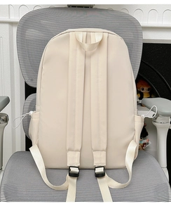 Detail view of wide cushioned shoulder straps on a light beige minimalist nylon backpack