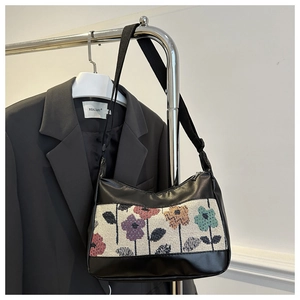 Detail view of floral tapestry canvas and black PU leather tote bag on a silver hanger
