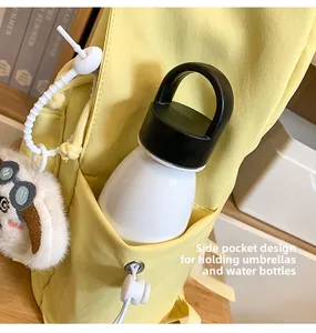 Detail of yellow backpack side pocket with drawstring holding water bottle and plush charm