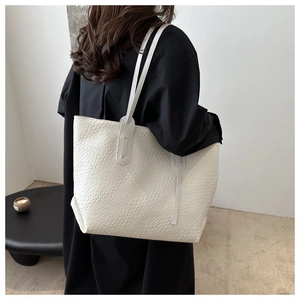 Detailed view of large white woven tote bag with slim dual straps on a model back