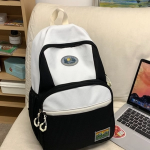 Large black and white nylon backpack with breathable mesh and mountain patches on sofa