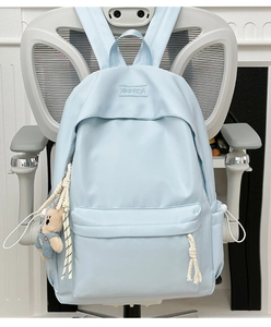 Detail of light blue waterproof nylon backpack featuring a cute bear plush keychain