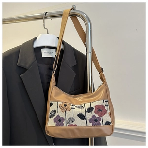 Close-up of floral jacquard fabric and khaki faux leather patchwork on a stylish hobo bag