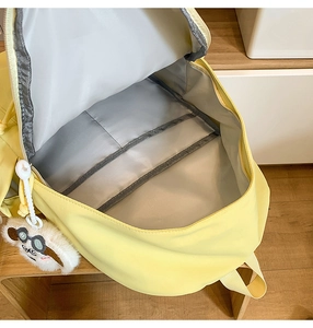 Detail view of the spacious inner grey lining and functional pockets of yellow backpack