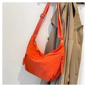 Détail d'un sac bandoulière orange vif en demi-lune avec fermeture éclair tissée élégante
