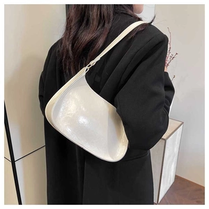 Detailed back view of a minimalist cream baguette bag worn with a black suit jacket