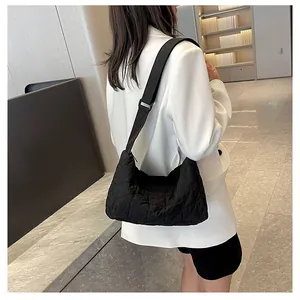 Rear view of a model wearing a black quilted tote bag with wide nylon shoulder strap