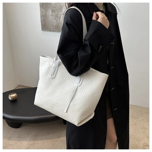 Detail of the white woven tote bag showing its intricate faux leather square texture