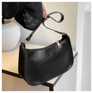Detail of vintage black crackle leather baguette bag with golden zipper and adjustable strap