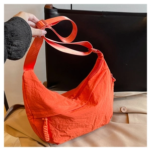 Détail d'un sac bandoulière croissant en nylon orange vif avec sangle large et fermeture