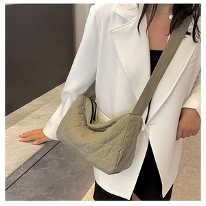 Detail of olive quilted tote bag with wide shoulder strap worn with a white blazer