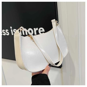 Close-up of white patent leather underarm bag with glossy finish and gold metal zipper