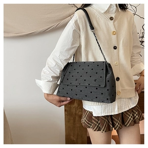 Détail du sac bandoulière en laine grise à pois noirs et bandoulière chaîne sur modèle