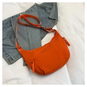 Gros plan sur un sac bandoulière orange vif en nylon léger avec fermeture à cordon tressé