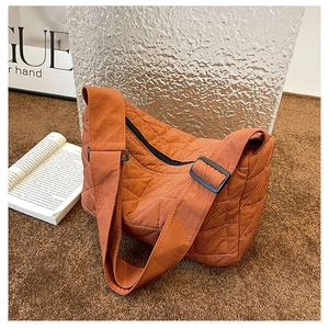 Detail of caramel quilted tote bag featuring nylon texture and wide adjustable strap