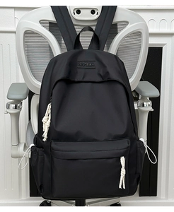 Close-up of black nylon backpack featuring XNFEIDA embossed logo and drawstring side pockets