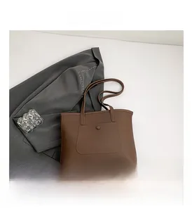 Detail view of a dark brown tote bag with decorative snap pocket and slim handles