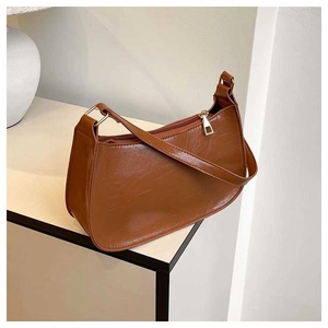 Detail view of the caramel brown vintage textured leather baguette bag with a metal zipper