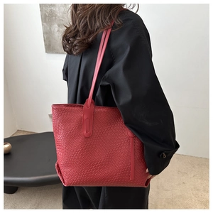 Close-up of the woven texture and slim straps on a large red tote bag for women