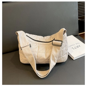 Close-up of cream quilted nylon tote bag with wide shoulder strap and black zipper