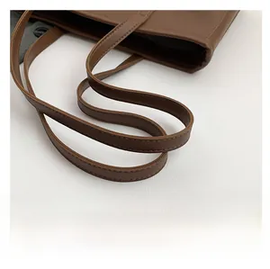 Close-up of comfortable shoulder strap with neat stitching on brown leather tote bag