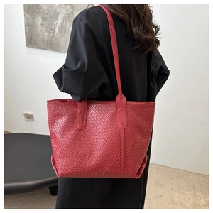 Detail of red woven tote bag with slim straps worn by a model in a modern interior