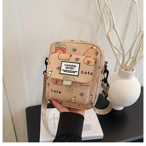 Détail du sac bandoulière en toile beige avec imprimés cartoons et sangle en nylon réglable