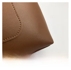 Close-up of brown pebbled leather texture and detailed stitching on the tote bag
