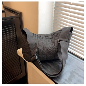 Detail of black quilted shoulder bag featuring waterproof nylon and wide strap