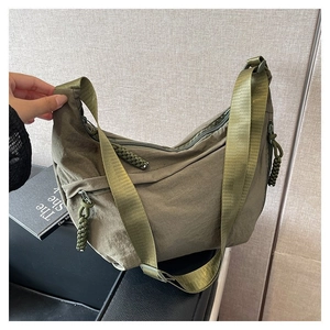 Détail d'un sac demi-lune en nylon vert armée avec tirette tissée et sangle