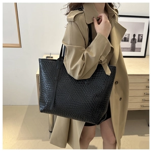 Close-up of woven black leather tote bag showing intricate checkered texture and handle detail