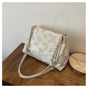 Détails de broderies papillon or et argent sur un sac cabas beige élégant