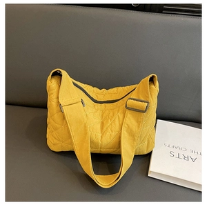 Detail of yellow quilted tote bag showing rhombus stitching and wide adjustable strap