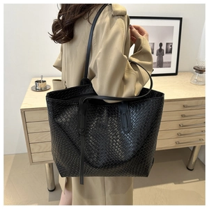 Detail of a large black woven tote bag featuring a matching detachable wristlet pouch