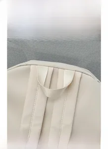 Detail display of the reinforced wide carry handle on this apricot minimalist backpack
