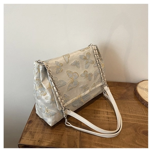 Détail du sac cabas en jacquard blanc avec élégantes broderies de papillons dorés et bleus