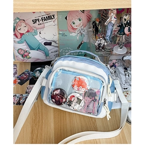 Détail du sac ita bleu clair avec fenêtre PVC montrant des badges anime sur bois
