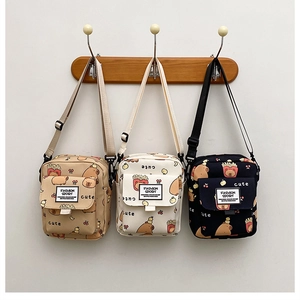 Détail de trois sacs à bandoulière en toile avec des motifs de dessins animés de capybara