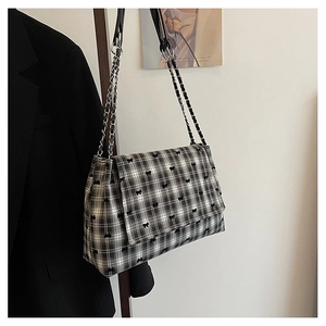 Détail de sac cabas à carreaux avec broderie nœud noir et bandoulière en chaîne métal