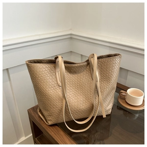Macro detail of beige woven tote bag texture with leather handle on wooden table