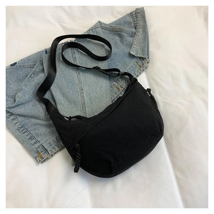 Détail du sac demi-lune noir minimaliste avec large bandoulière en nylon réglable