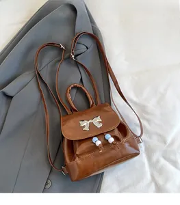 Close-up of brown vintage butterfly mini backpack with silver bow and pearl pendant