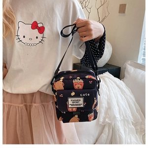 Détail du sac bandoulière noir avec imprimés cartoon et bandoulière réglable en nylon